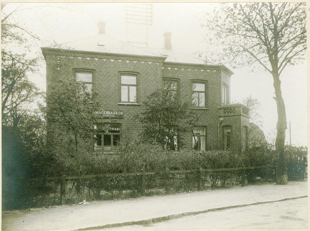 Chr. Nicolaisens hus på Stationsvej. Bankfilial og telefoncentral. Bemærk stativ til luftledninger. Bagermester Georg Ibsens villa på Linde Allé 1 blev opført af murermester Valdemar Holm i 1926. Dette foto er gengivet i et skrift fra januar 1928 og foto må derfor være fra 1927. Foto fra Amagerbankens billedsamling.