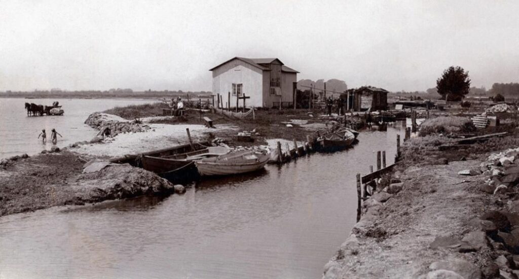 Walløes Havn omkring 1910. Her var dels plads til mindre både, dels en lille badestrand (til venstre i billedet). Ved havnen havde maleren Chr. Mølsted i en periode sit atelier. Det er den store bygning midt i billedet. Bemærk også blegevognen ude i vandet til venstre. Når lærredsstykkerne var blevet bleget, skulle de skylles, og de foregik fra stranden.  Foto: DB Arkiv.