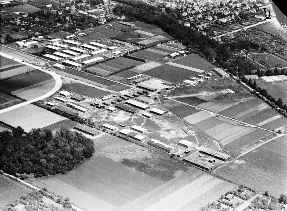 1946. Området med Flygtningelejr nr. 126. Laden ses lige uden for lejren ud for den runde lyse stribe, der en tysk rullebane, hvis forløb gav tilnavnet til området ”Den kvarte Lagkage”. I perioden 1945-47, da lejren eksisterede, blev laden anvendt som depot af lejradministrationen. Foto: Sylvest Jensen, DB-Arkiv.