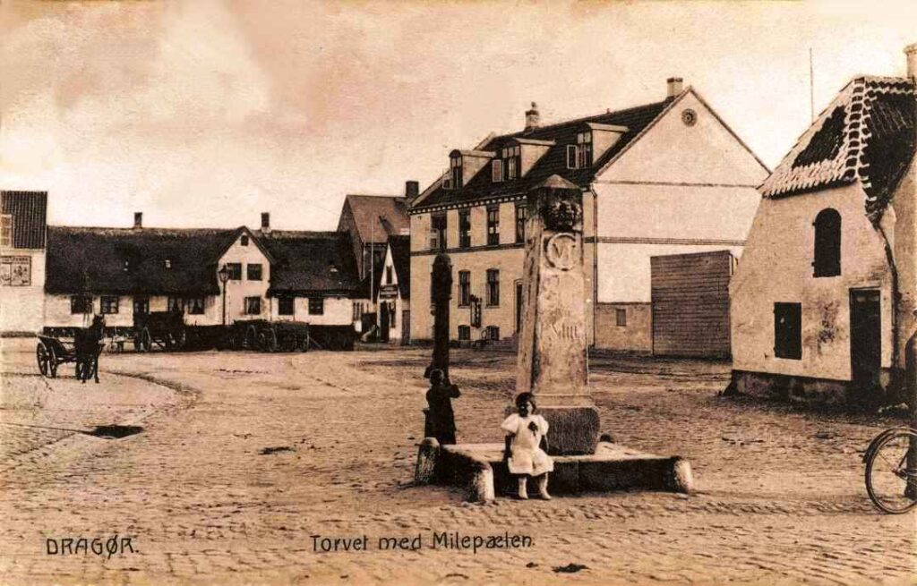 Badstuevælen ca. 1906. Dragør Vandværk åbnede i 1907 samtidig med Amagerbanen og gradvis blev de 9 offentlige vandposte lukket. Vandposten ved milepælen havde tidligere stået mere tæt på Kongevejen. Foto: DB-Arkiv.