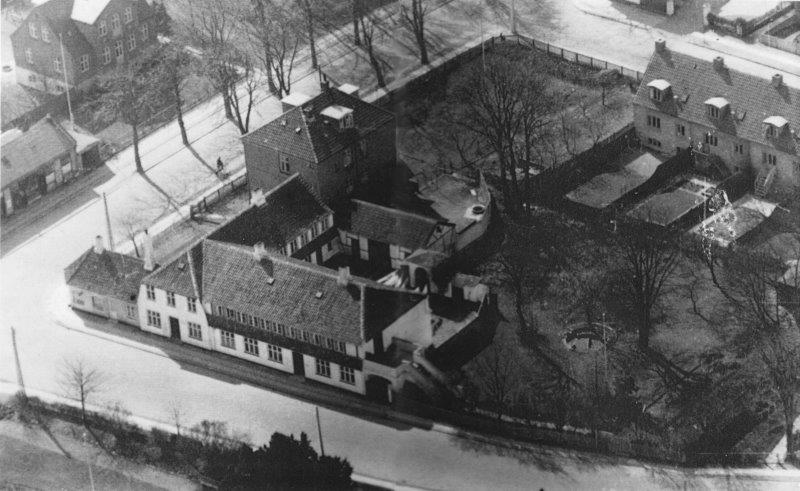 Da bankfuldmægtig Helge Otzen omkring 1950 ejede "Høyerup" fik han taget et foto af hele området. Via en smal port kom man ind i gården bag "Høyerup". På dispensation havde repræsentant Carl Johannes Høyers, Villa Dalhøj (nuv. Menighedsbørnehave) fået tilladelse til at opføre en garage helt ud til Kirkevej i 1924. Foto: DB-Arkiv.