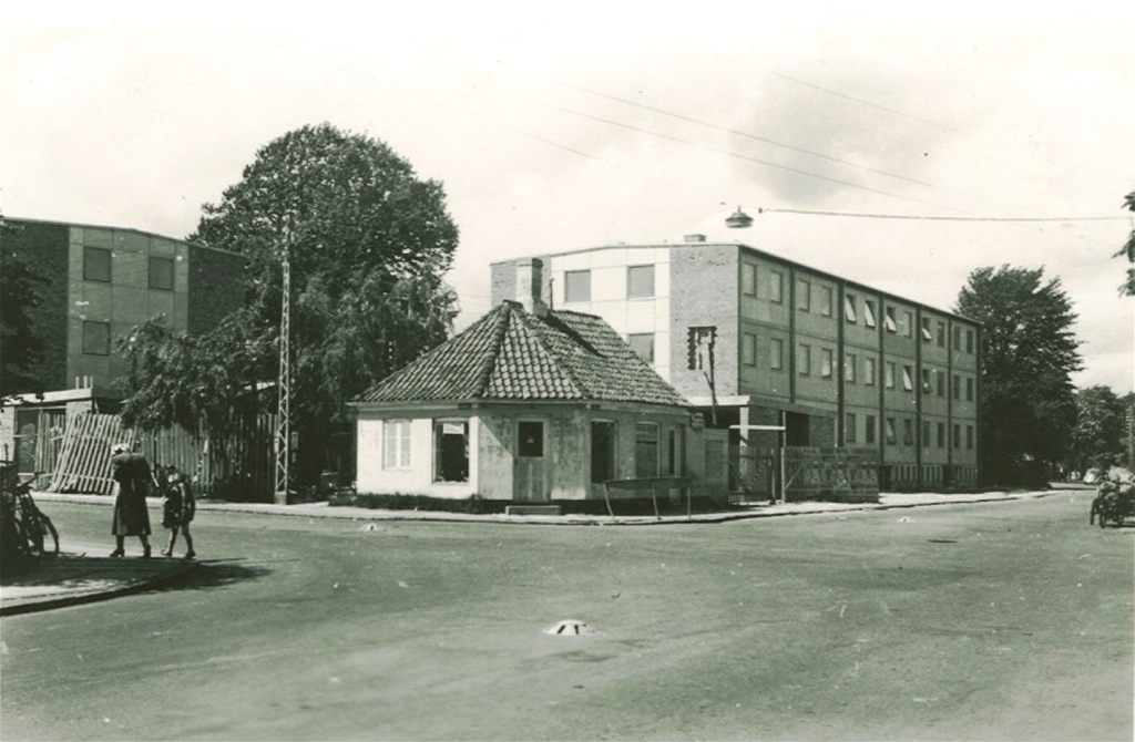 15. juni 1957. "Kokken" har drejet nøglen om. Den 7. august 1957 rykkede Amagerbanken fra Stationsvej 7 til hjørnet og beboerne flyttede ind på Stationsvej 2-6 og Linde Allé 16-20. Bemærk relief med Amagerbankens logo på sydgavlen af Stationsvej 2. Stadig synlig i mange år under bestemte lysforhold. Foto: Museum Amager.