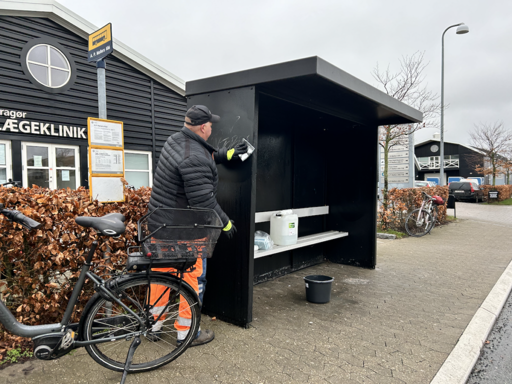 Ole H. Hansen renser graffiti af ved et busstop i Dragør. Foto: Dragør News 