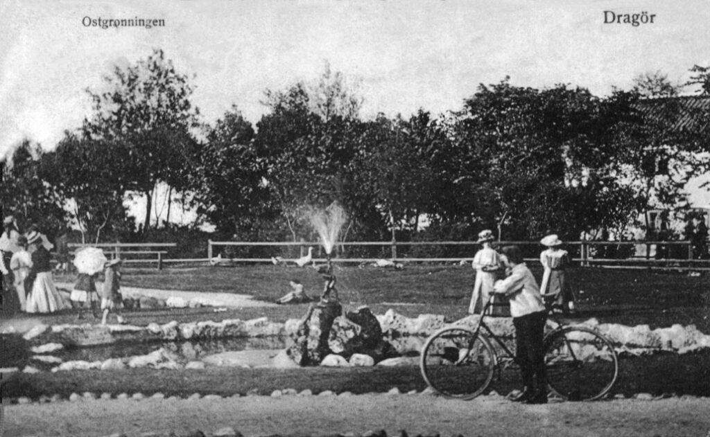 Postkort fra ca. 1910 set mod E.C. Hammersvej Et af de få postkort, hvor man kan se vandet springe ud af fiskens mund. Bemærk at pladsen bliver benævnt "Østgrønningen". Postkort udlånt af Jørgen Aamand.